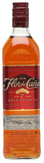 A bottle of Flor de Caño 7 Years Gran Reserva rum, showing the amber-colored liquid inside a clear glass bottle with a dark red label and cap, set against a plain white background.